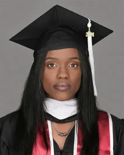 Graduate in black cap and gown with red stole, facing forward against a gray background.