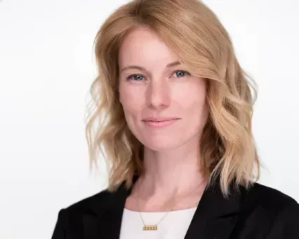 Portrait of a blonde woman in a black blazer against a white background
