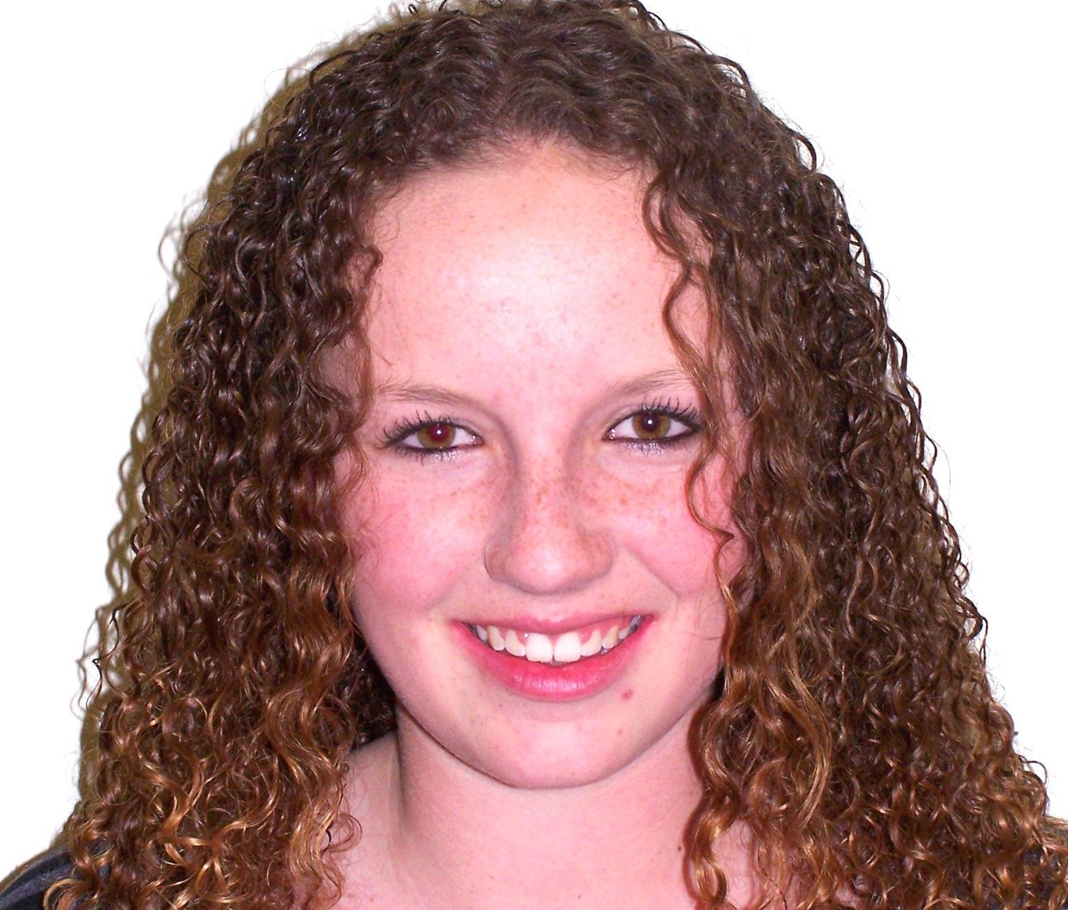 A woman is smiling and wearing a white shirt