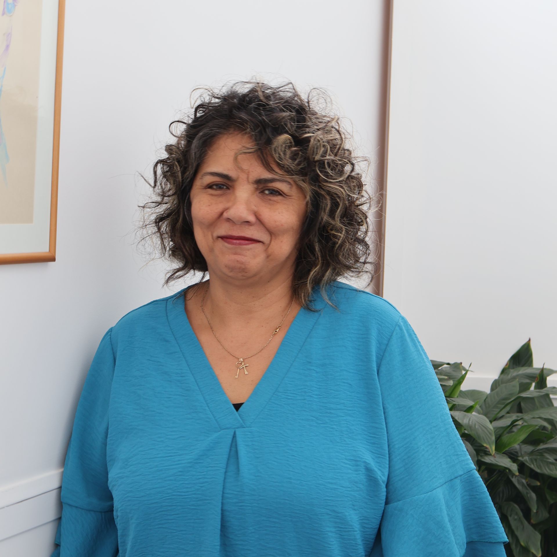 A woman with curly hair is wearing a blue shirt