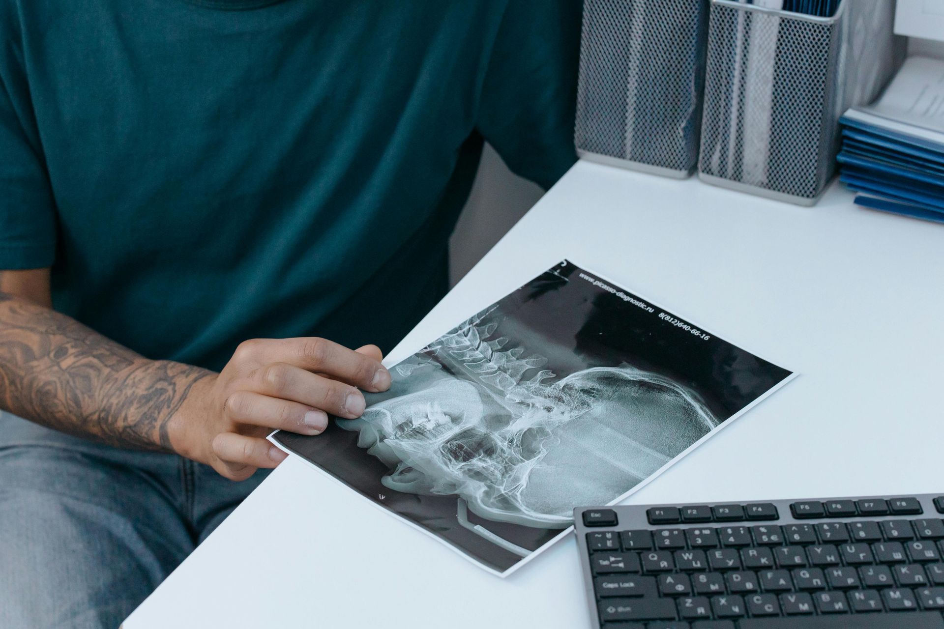 A man is sitting at a desk looking at an x-ray of a skull.