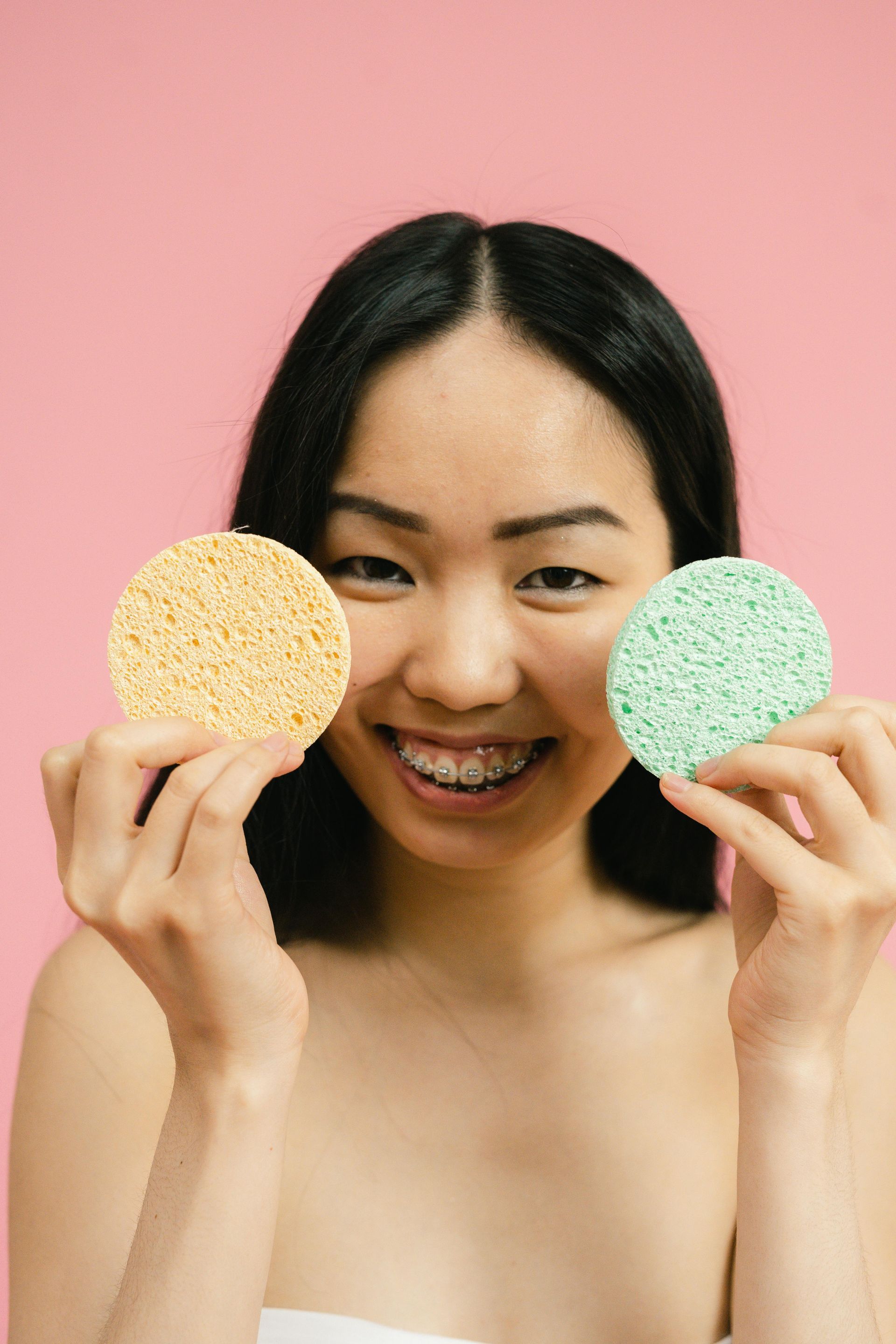 A woman is holding two sponges in front of her face.