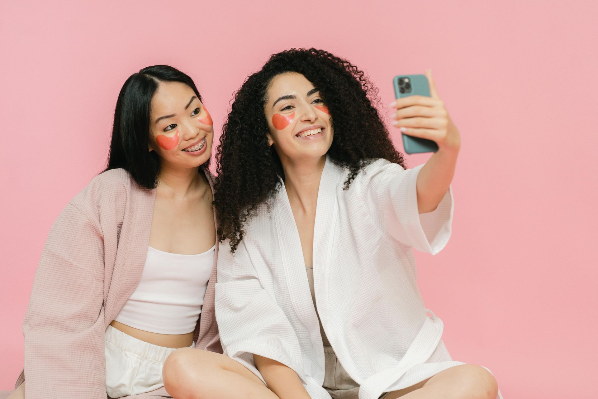 Two women are taking a selfie with their faces painted.