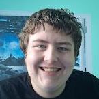 A young man is smiling in front of a picture on the wall.