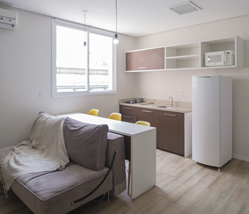 Uma sala de estar com sofá, mesa e geladeira