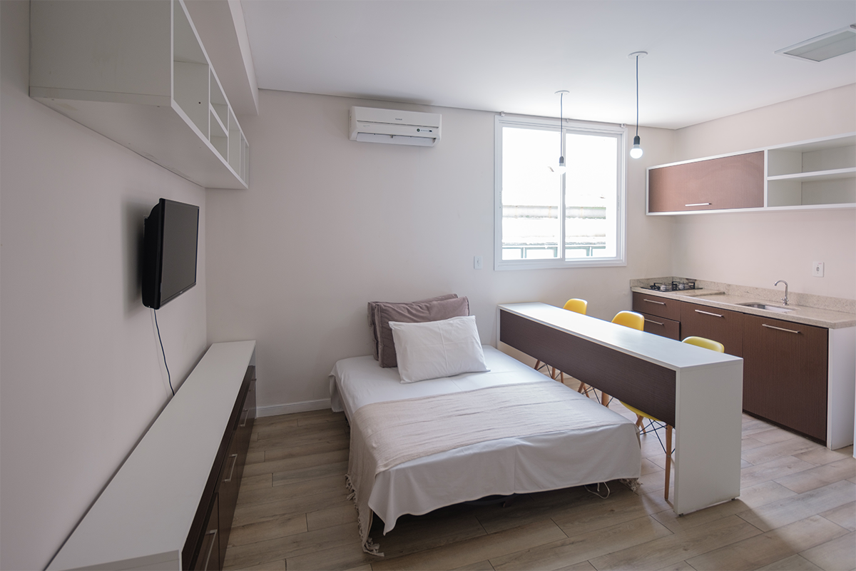 Um quarto com uma cama e uma cozinha ao fundo