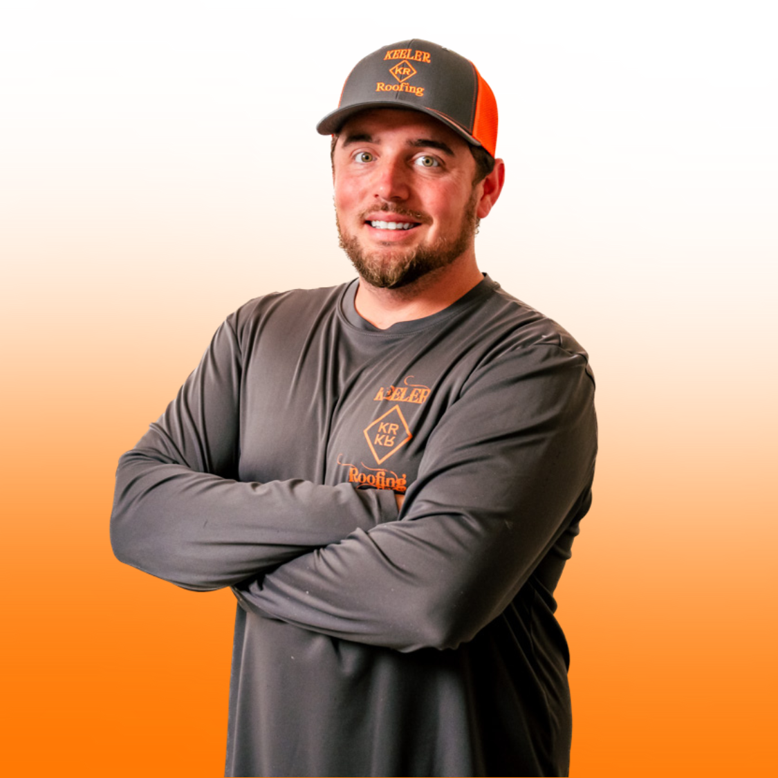 A man wearing a hat and a long sleeve shirt is standing with his arms crossed