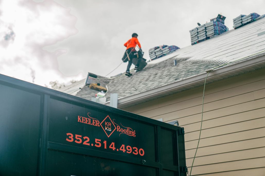 Roofing professionals in Florida transporting construction materials on a rooftop.