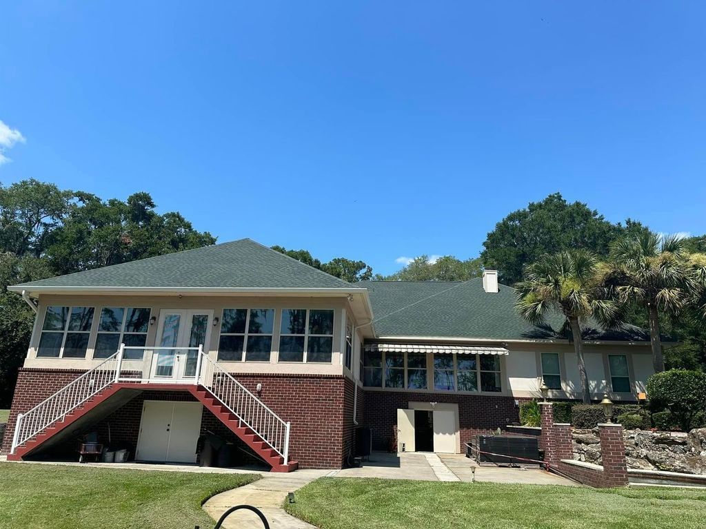 A large ranch-style home featuring a red brick lower level and a beige upper floor with a sunroom