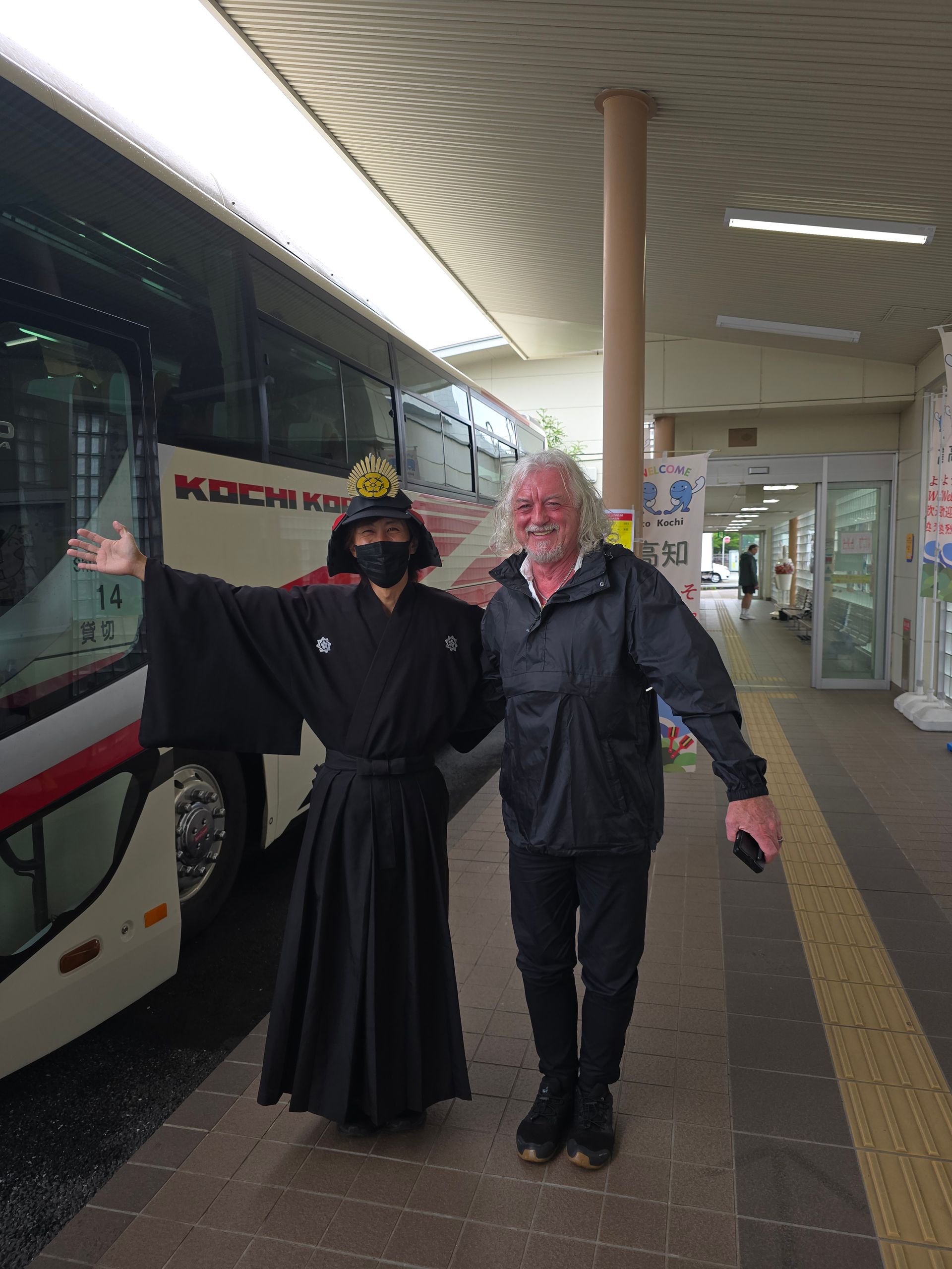 A man in a samurai costume is standing next to another man