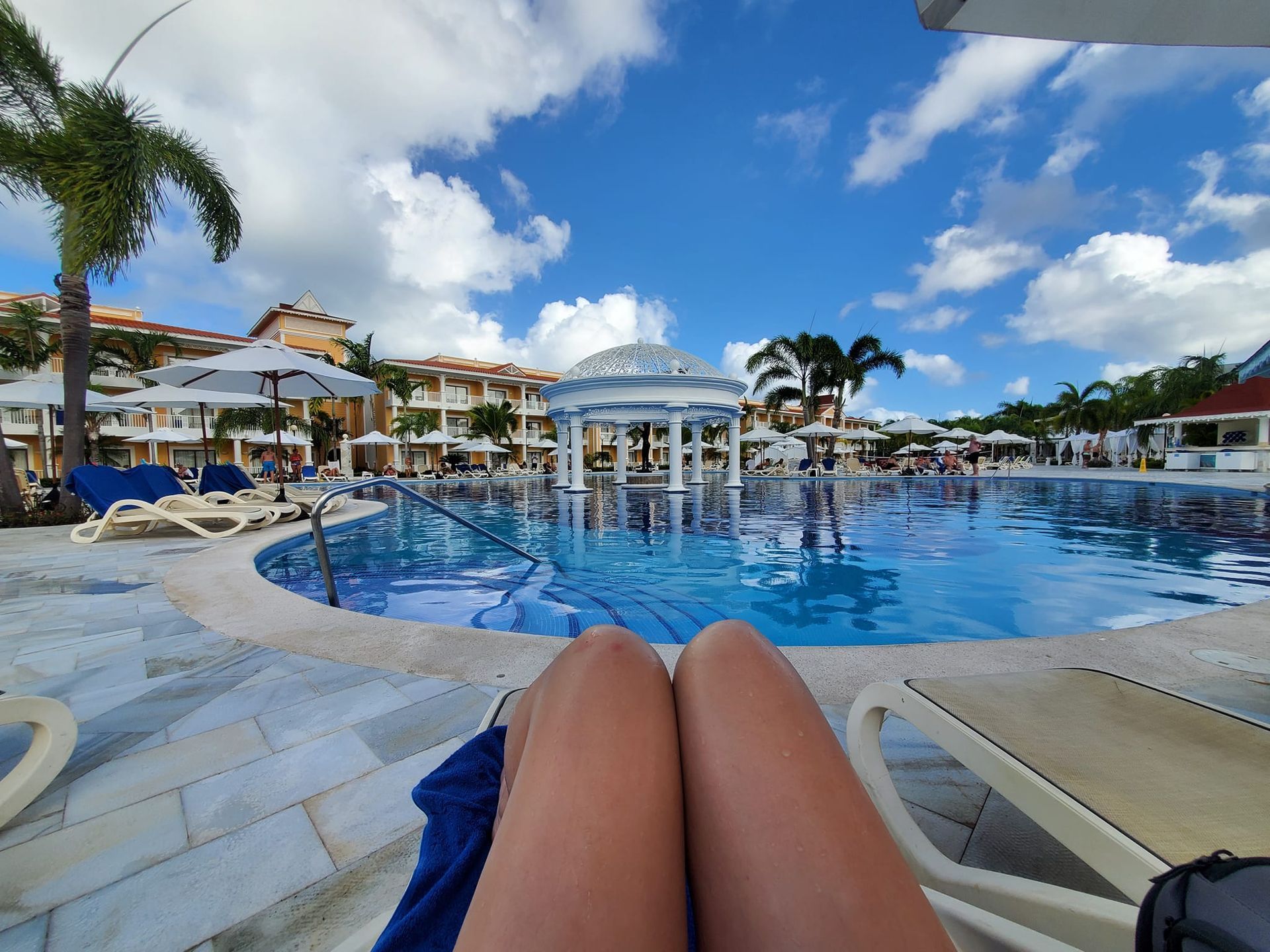 A woman is sitting on a chair in front of a large swimming pool.