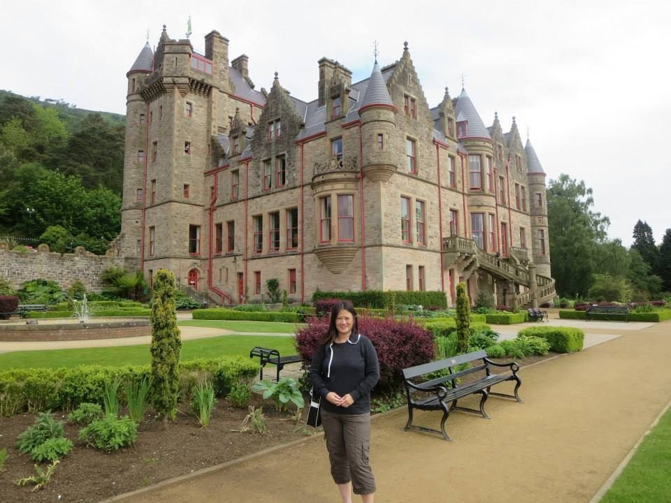 A woman is standing in front of a large castle.