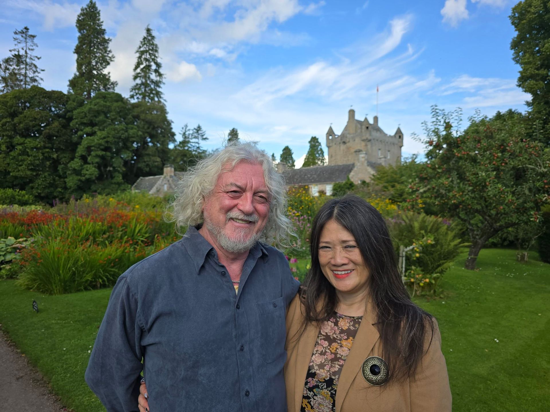 A man and a woman are posing for a picture in front of a castle.