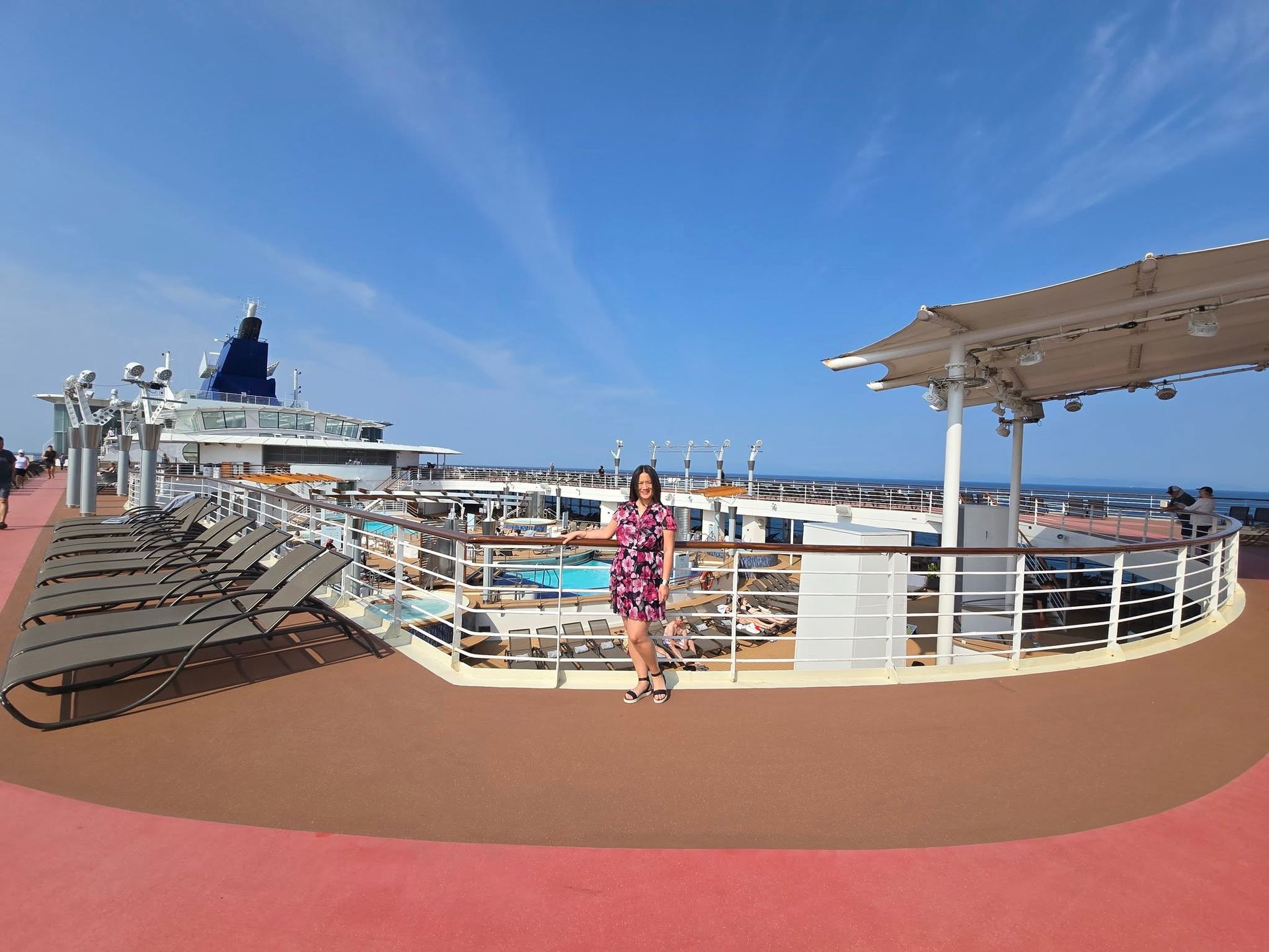 A woman is standing on the deck of a cruise ship.