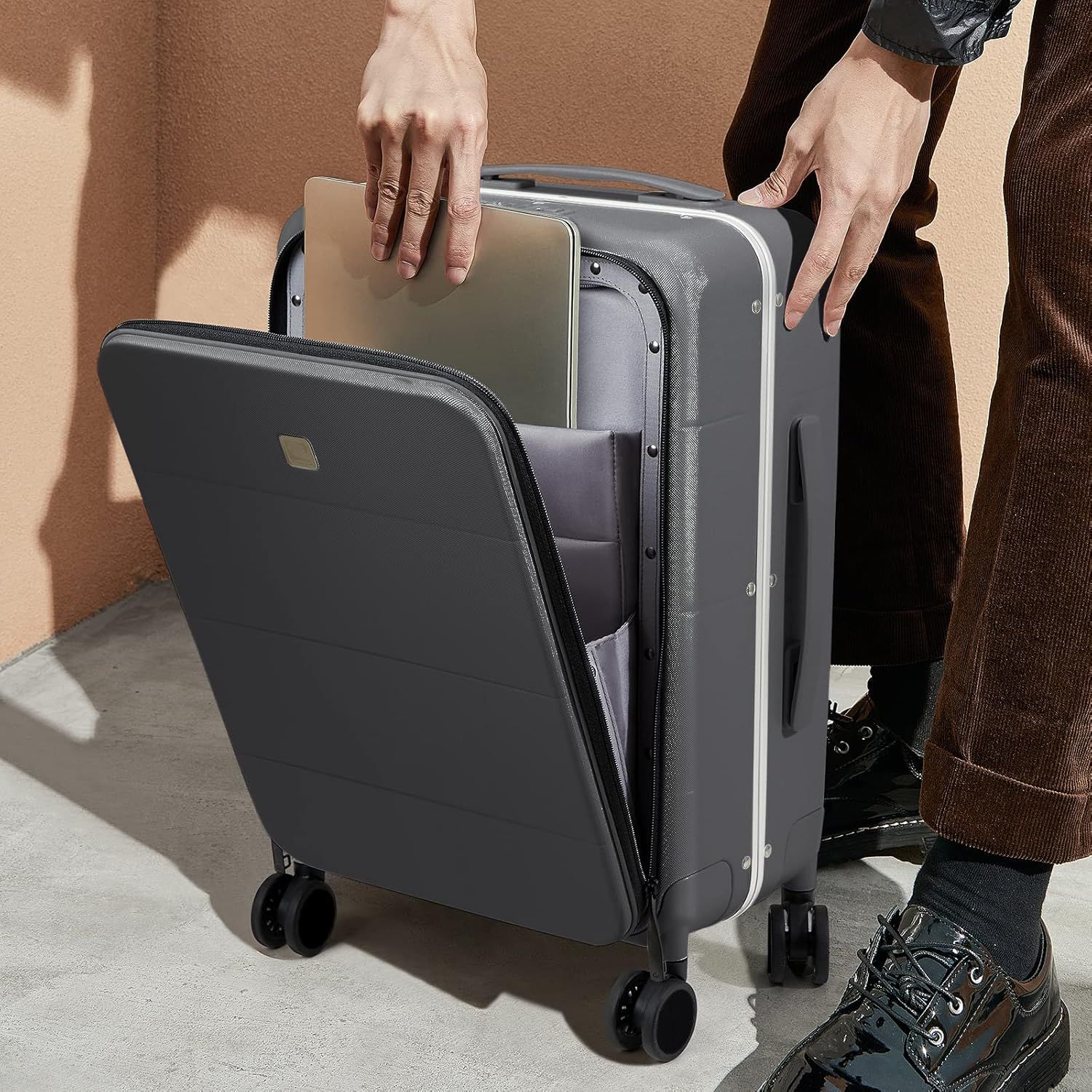 A person is putting a laptop into a suitcase.