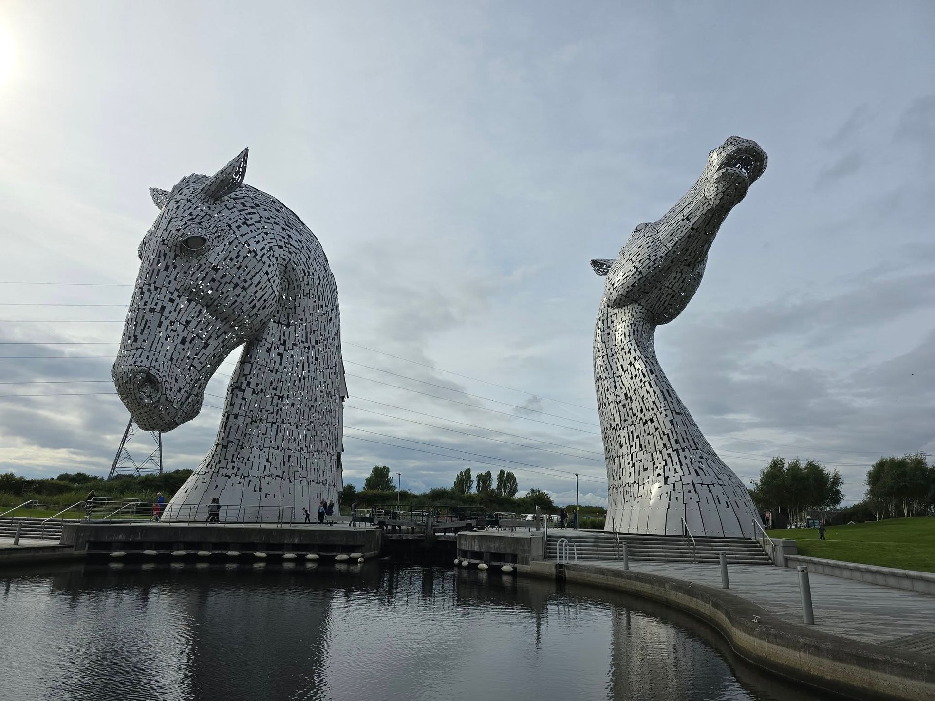 Two sculptures of horses are standing next to each other in front of a body of water.
