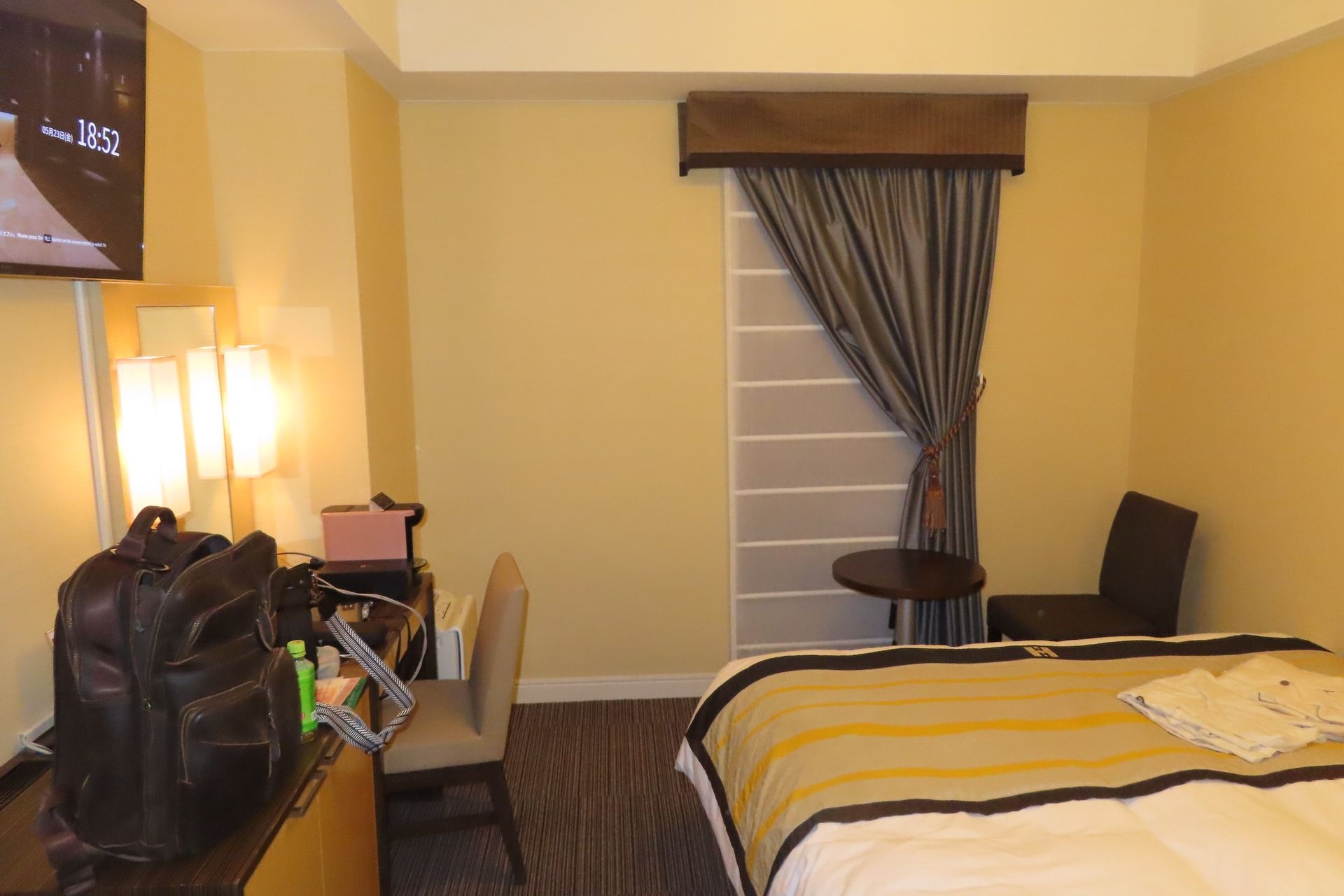 A hotel room with a bed a desk and a television