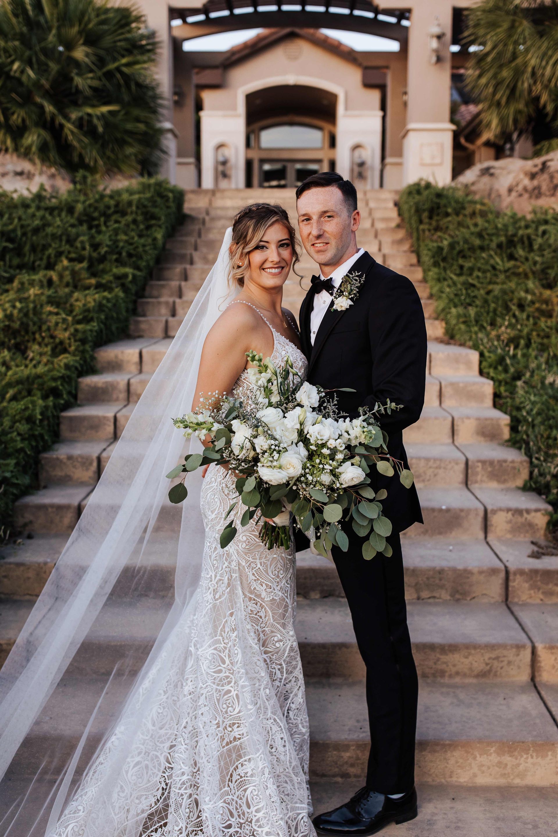 a bride and groom pose for a picture on a set of stairs