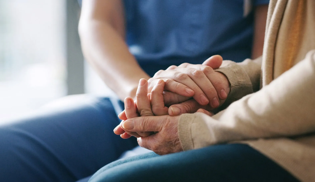 Due persone che si tengono per mano in un momento intimo e di sostegno reciproco su un divano.