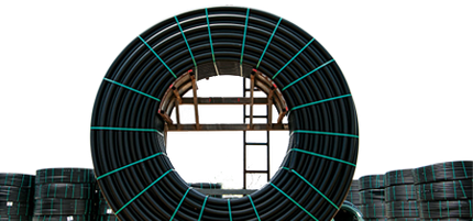 A large spool of black plastic pipe with green ties around it.