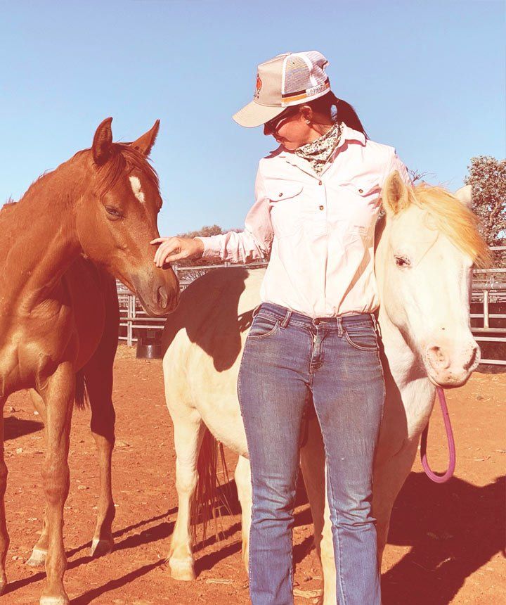 An animal nutritionist is standing next to two horses one brown and one white