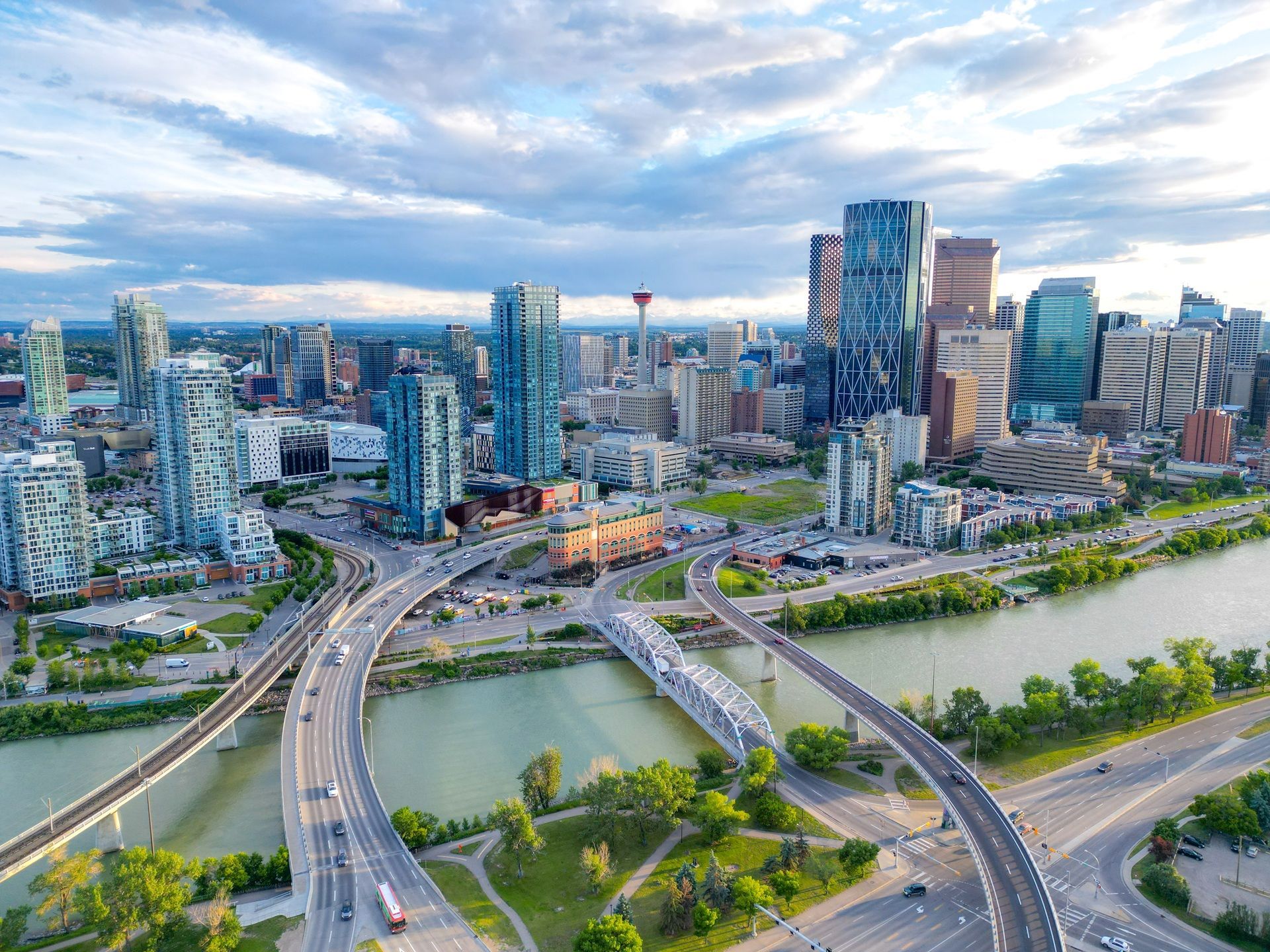 Luchtfoto van een moderne stadsgezicht op Calgary met een rivier, bruggen en snelwegen bij zonsondergang.