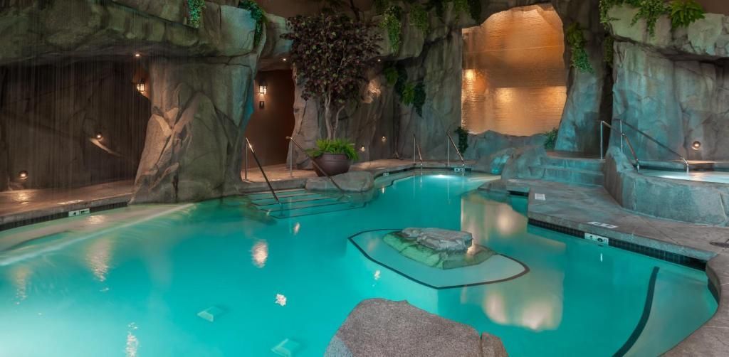 Overdekt zwembad in grotstijl met turquoise water, watervallen en rotswanden.