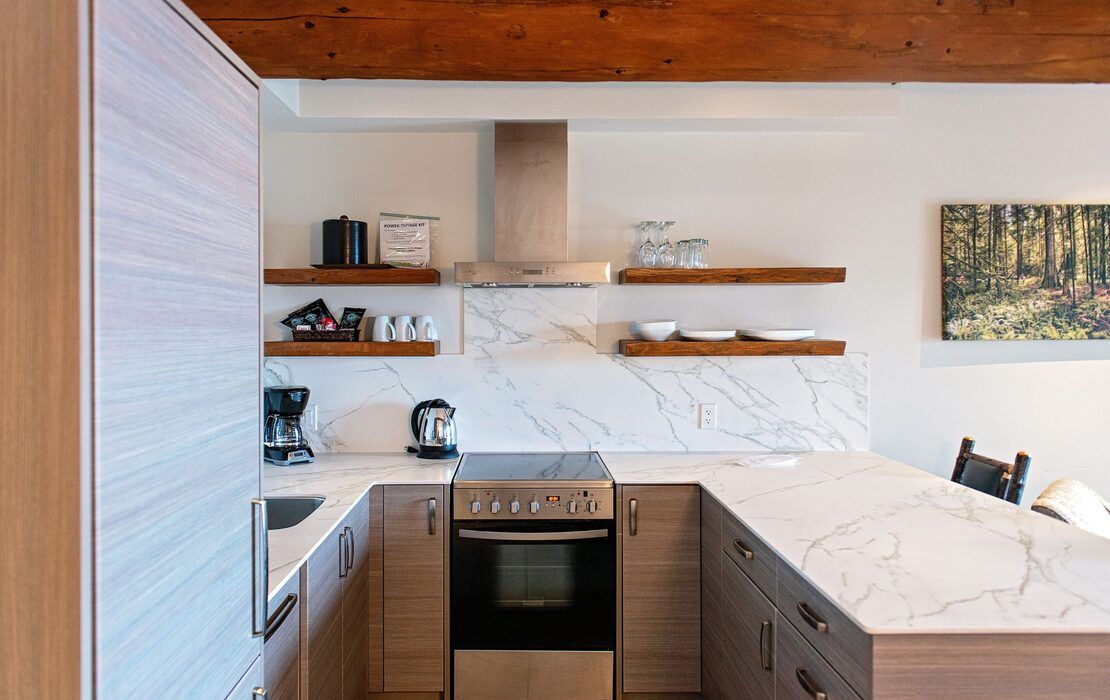 Moderne keuken met houten accenten, marmeren werkbladen, open planken en een roestvrijstalen oven.