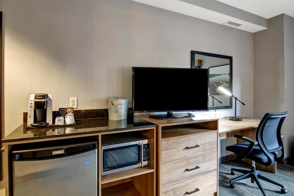 Hotelkamer met bureau, tv, minikoelkast, koffiezetapparaat, ladekast en bureaustoel.