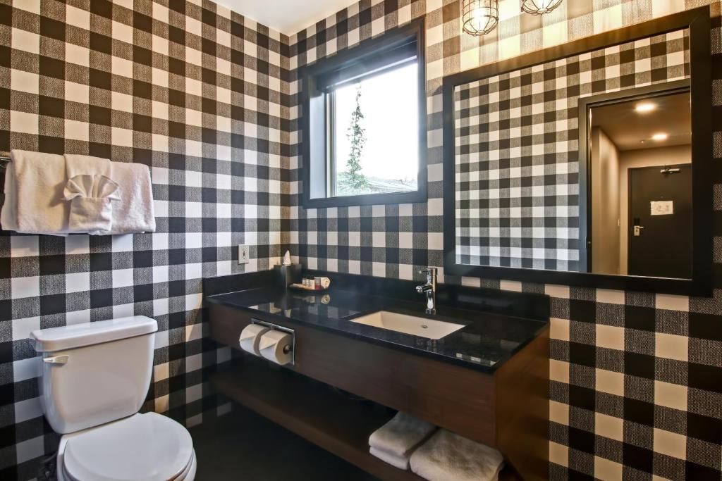 Zwart-wit geblokte badkamer met toilet, wastafel, spiegel en handdoekrek aan de muur.