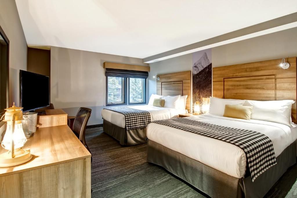 Moderne hotelkamer met twee bedden, bureau, tv, raam en warme houten lambrisering.