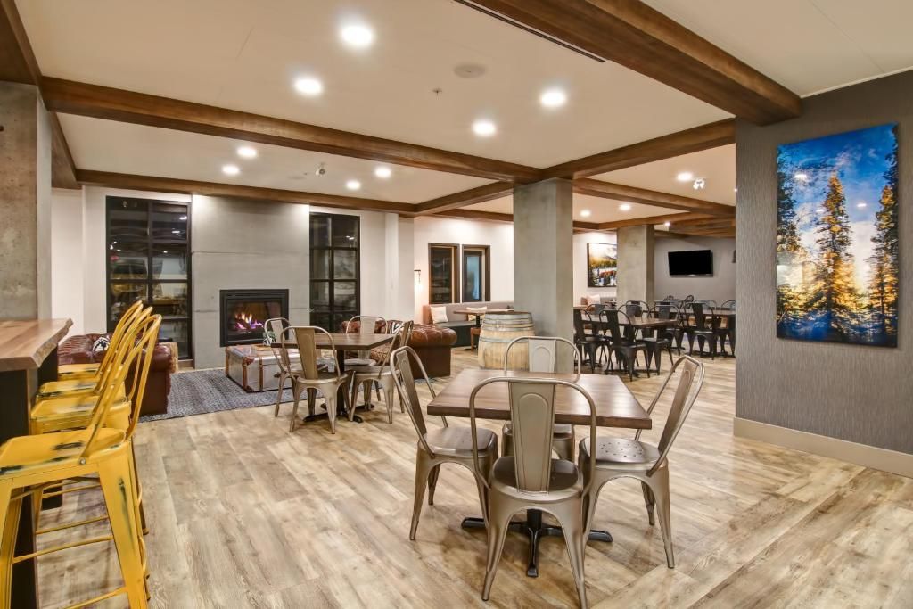 Ruime eetzaal met houten tafels, stoelen en sfeervolle plafondverlichting.