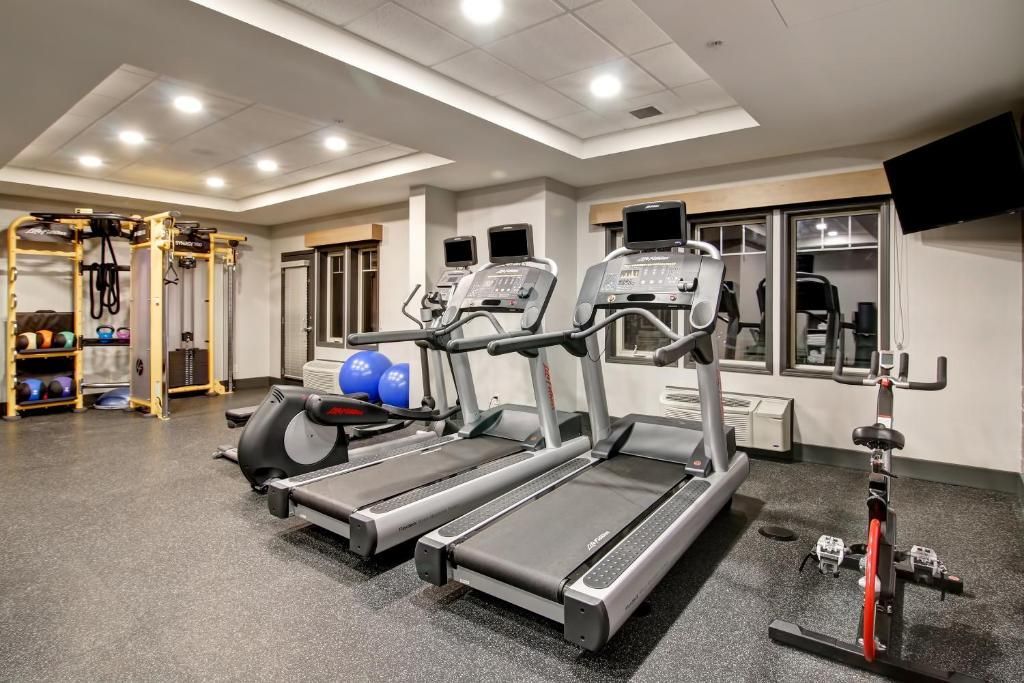 Moderne fitnessruimte met loopbanden, gewichtsapparaten, spiegels en plafondverlichting.