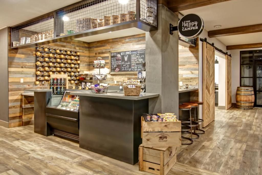 Gezellige bakkerijcafé-interieur met vitrine, planken vol potten en rustieke houten accenten.