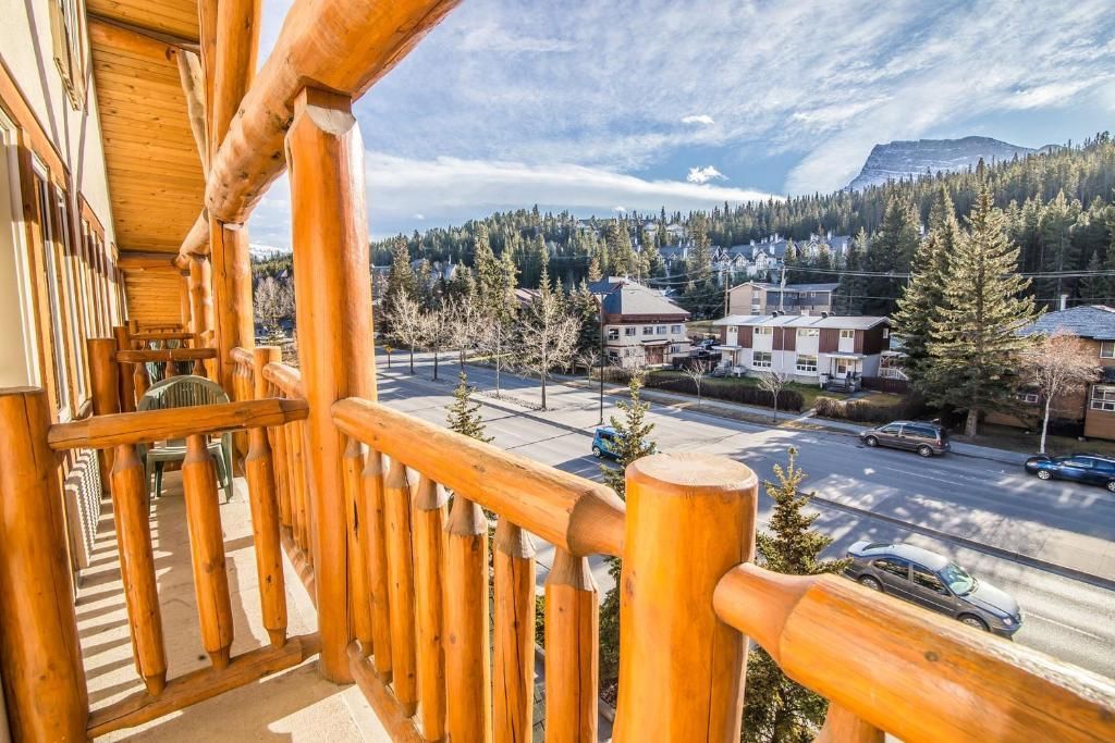Houten balkon met uitzicht op een besneeuwd bergdorp met bomen en gebouwen onder een heldere hemel.