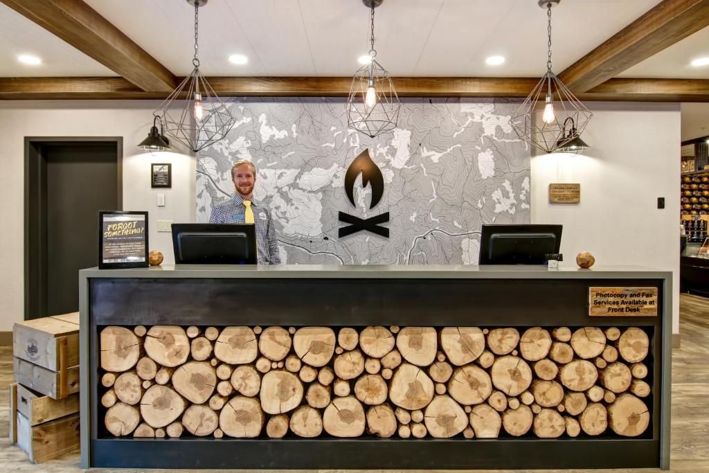 Hotelreceptiebalie met front van boomstammen, grijze wanddecoratie en hangende pendellampen