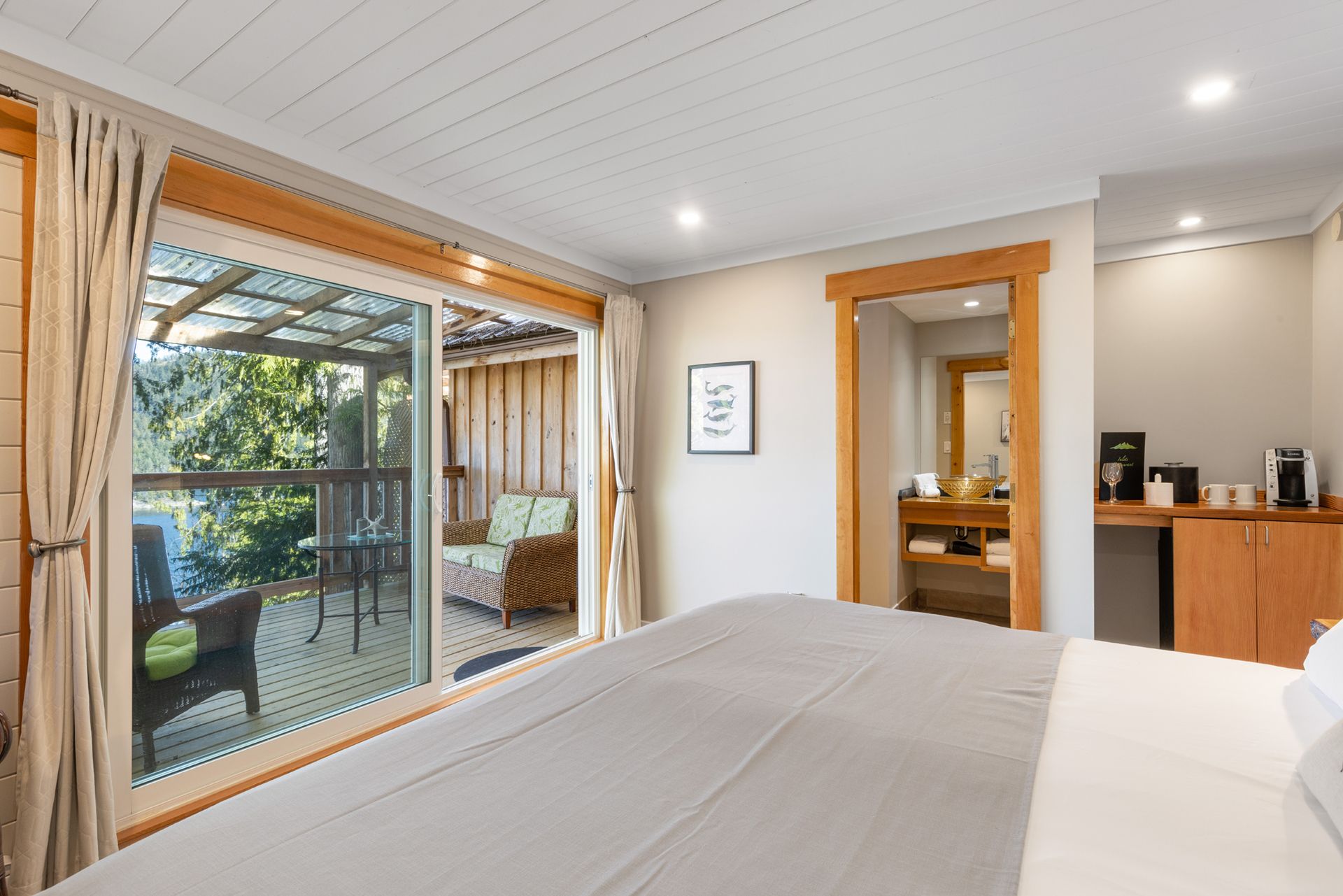 Lichte slaapkamer met schuifdeuren van glas die toegang geven tot een overdekt terras en tuin.