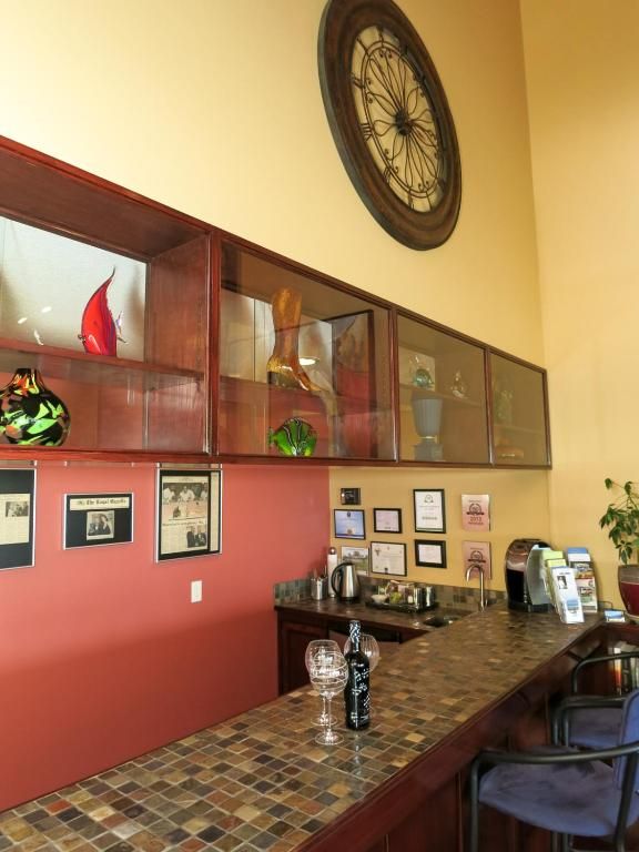 Een café-interieur in warme tinten met een lange toonbank, wandplanken, ingelijste decoraties en een ronde klok erboven.