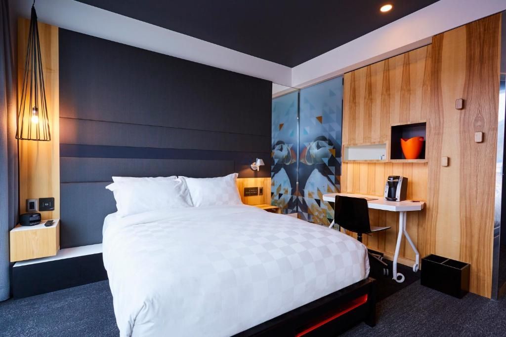 Moderne slaapkamer met een groot wit bed, een donkere accentmuur, een houten kledingkast en een bureauhoek.