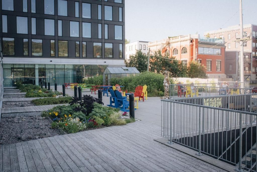 Moderne binnenplaats met kleurrijke banken, planten en een houten terras naast een balustrade.