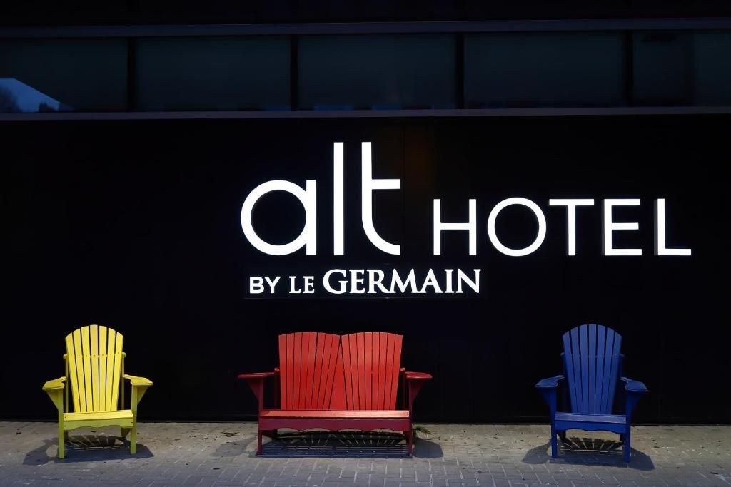 ALT HOTEL-bord met gele, rode en blauwe stoelen ervoor.