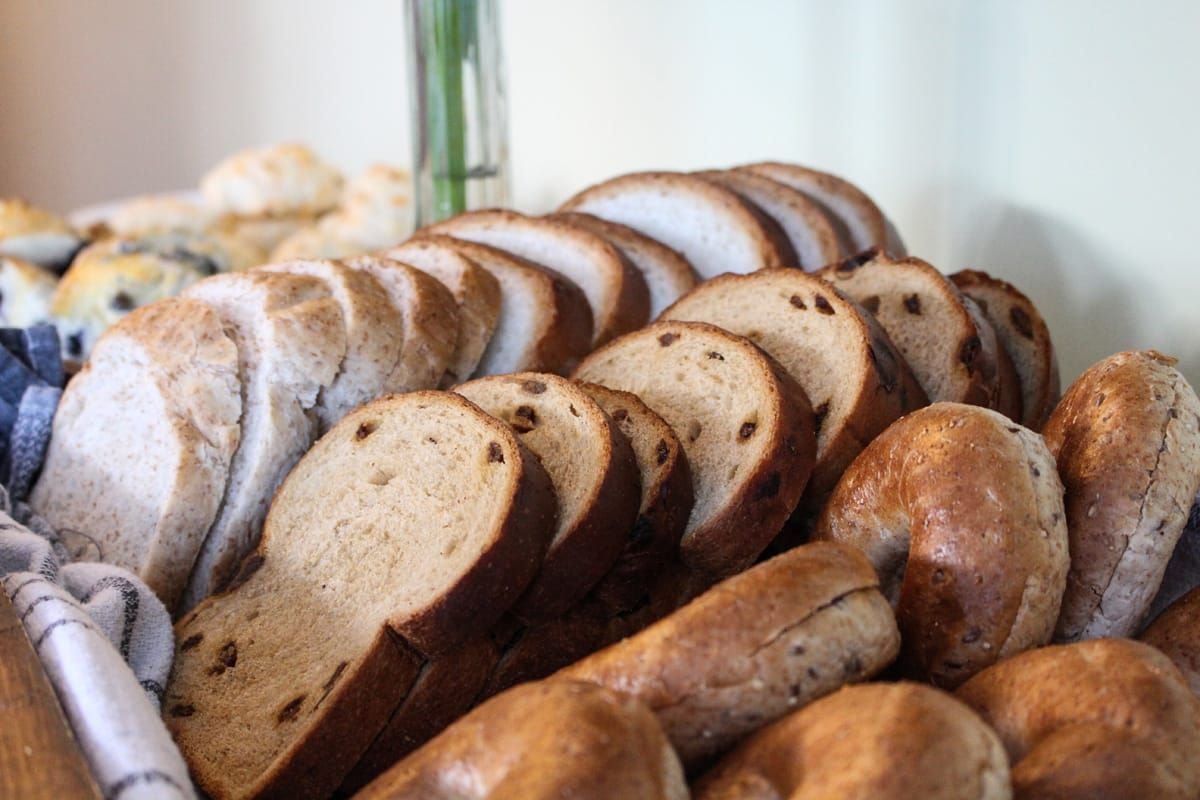 Diverse soorten ambachtelijk gesneden brood, gestapeld in een mand, met knapperige broden en licht en donker brood.