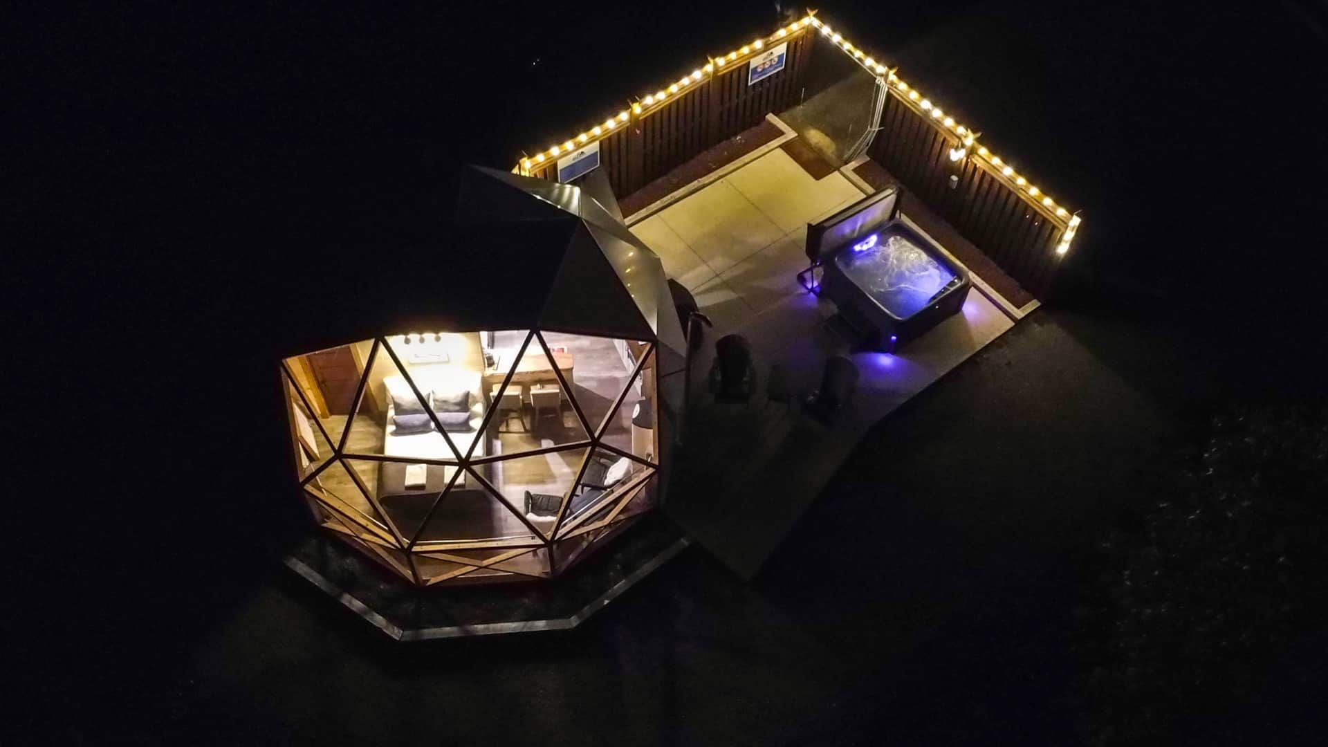 Nachtopname vanuit de lucht van een verlichte dome van Appalaches Domes met een verlichte jacuzzi.