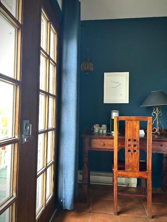 Houten bureau en stoel naast een zonovergoten deur in een kamer met blauwe muren.