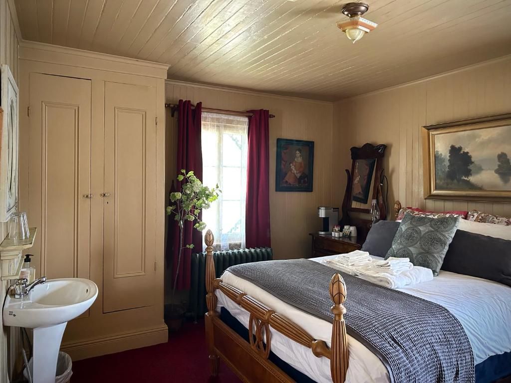 Gezellige slaapkamer met twee eenpersoonsbedden, een beige kledingkast, een witte wastafel en een raam met paarse gordijnen.
