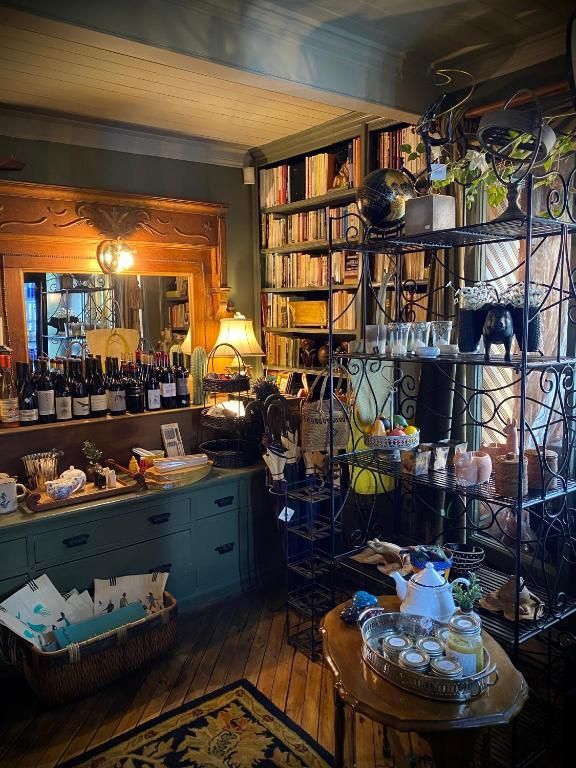 Gezellige woonkamer met boekenkasten, een spiegel met lamp, een turquoise dressoir, planten en een klein rond tafeltje met theekopjes.