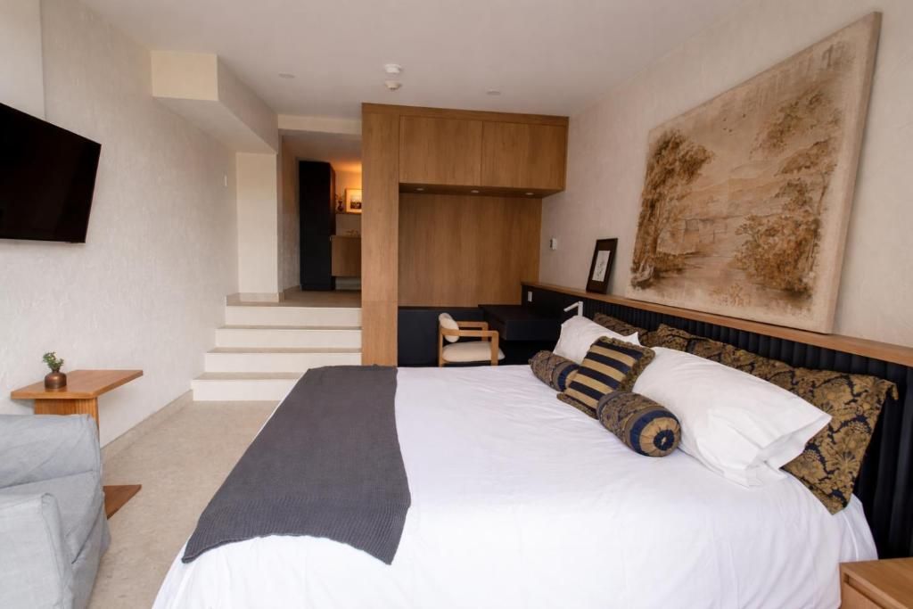 Moderne slaapkamer met een groot bed, houten accenten, witte muren en een trap naar een mezzanine.