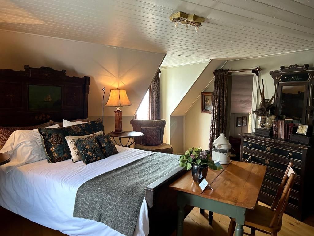 Gezellige slaapkamer met een groot bed, houten bureau, lamp en vensterbank in warm licht.