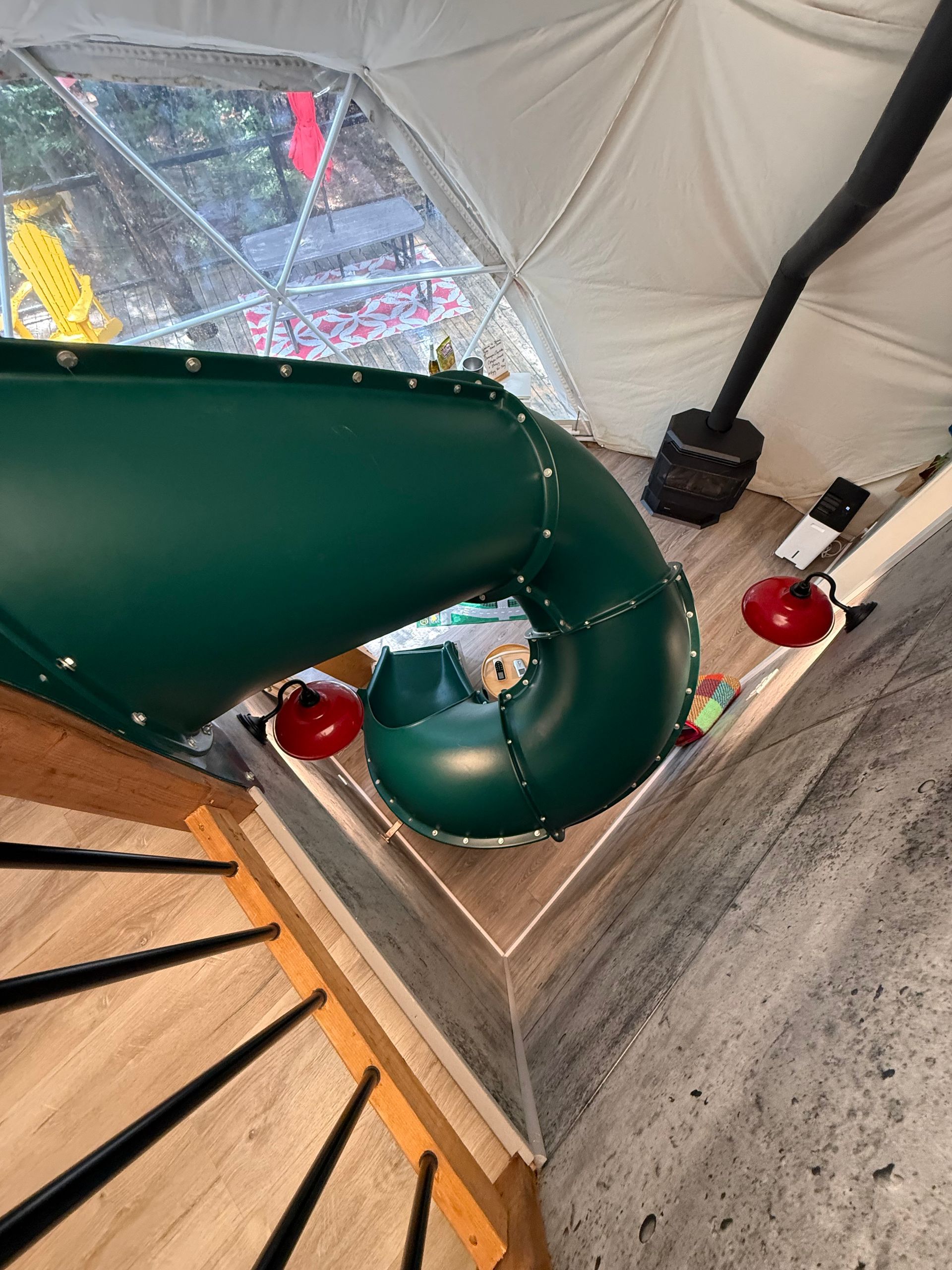 Groene spiraaltrap in een dome tent van Balsam Ridge Forest Domes, van bovenaf gezien, met houten trap en rode lampen.