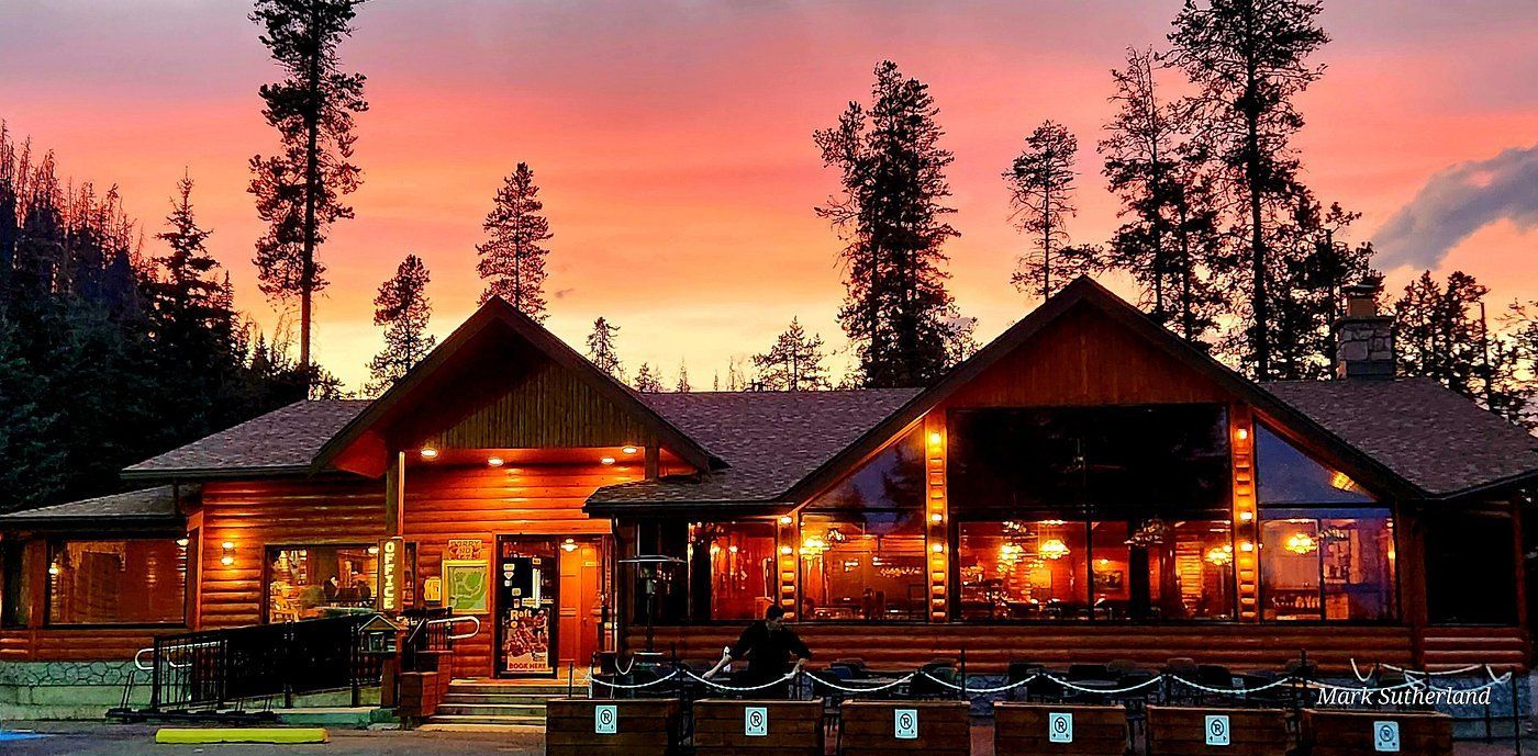 Zonsondergang boven de receptie van Becker's Chalets in Jasper met warm licht en een roze-oranje hemel.